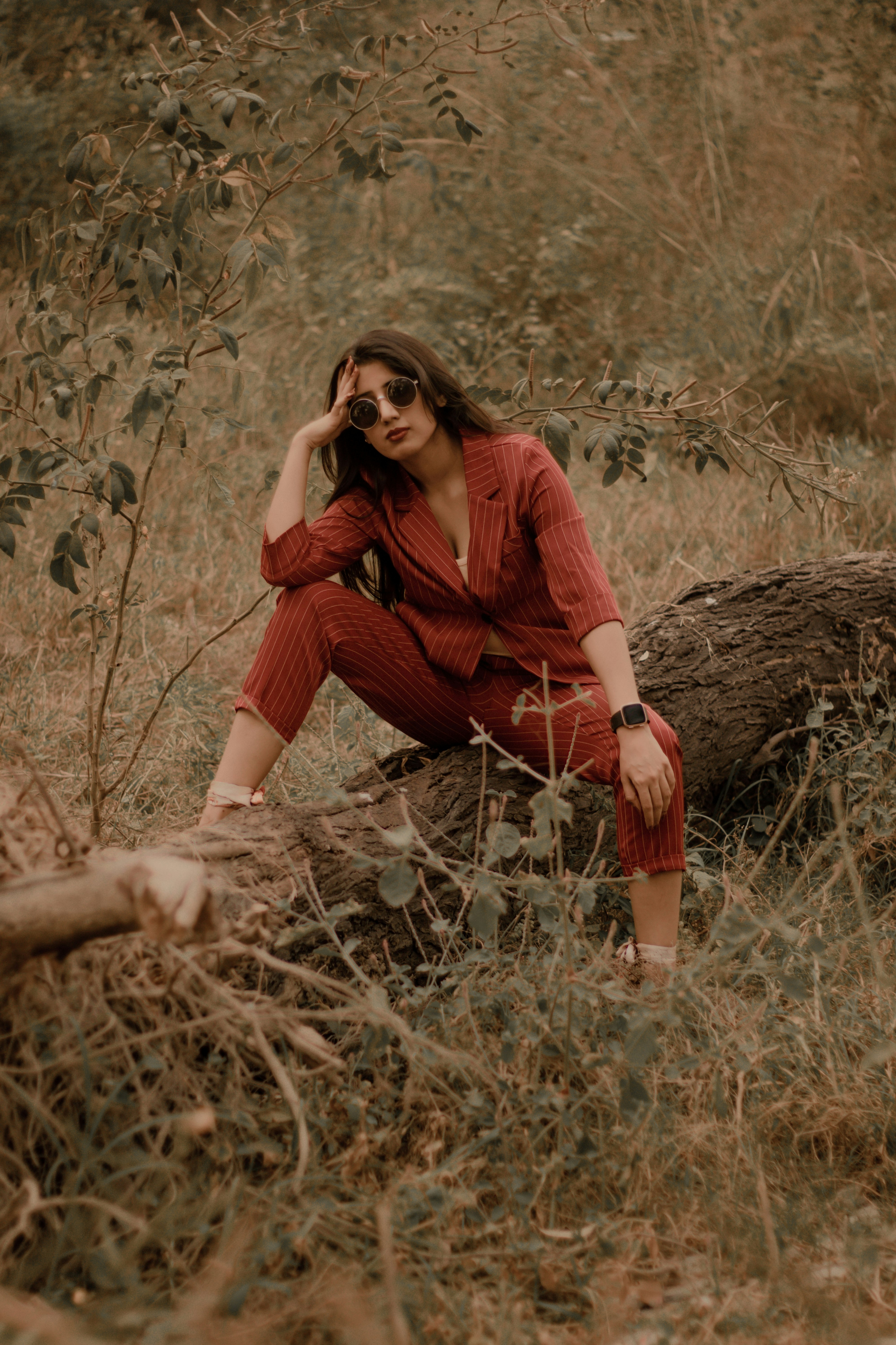 woman in red long sleeve shirt and brown pants sitting on brown grass during daytime